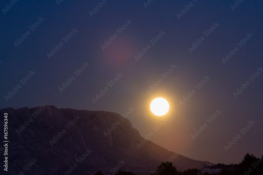 Rise of super big Moon over the mountain Sainte Victoire