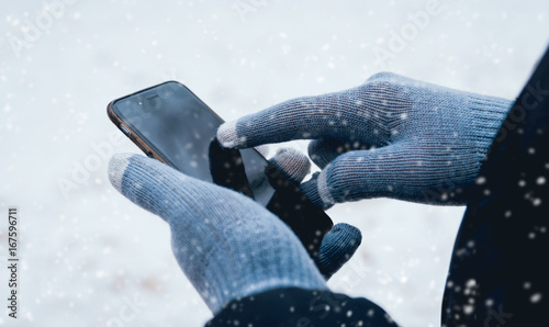 Man using smartphone in winter with gloves for touch screens