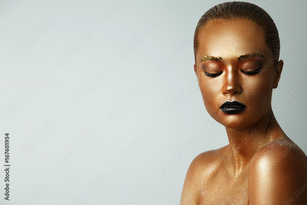 Girl with golden paint on her face. Black lipstick on lips. Creative make up, face art, body art Girl with golden paint on her face. Black lipstick on lips. Creative make up, face art, body art