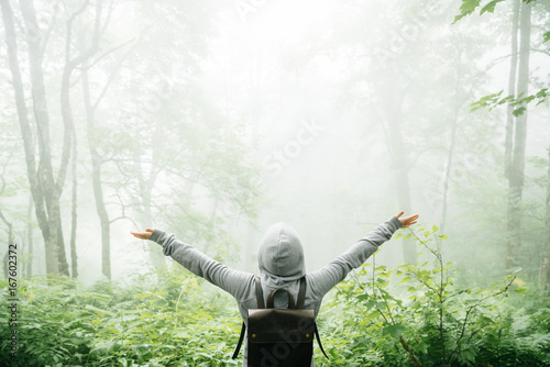 Freedom traveler stood with his arms raised and enjoying the beautiful nature with fog.