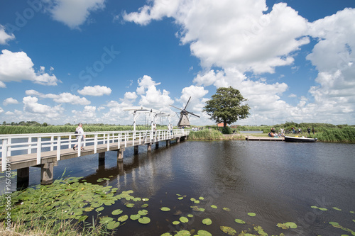Old bridge and windmill across a canal