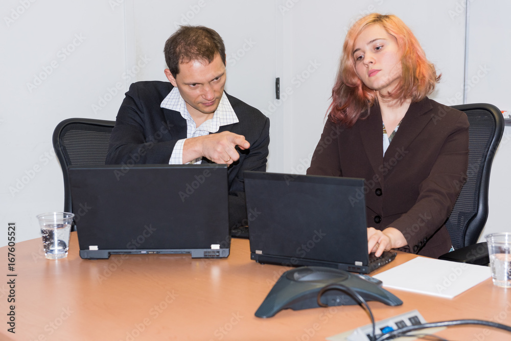 Young business woman and man pointing to laptop and thinking Young business woman and man pointing to laptop and thinking