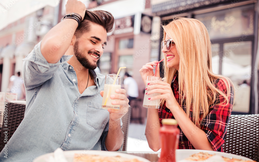 Beautiful young couple sitting in the cafe and eating pizza. Consumerism, food, lifestyle concept Beautiful young couple sitting in the cafe and eating pizza. Consumerism, food, lifestyle concept