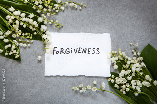 Forgiveness word on gray background with white flowers