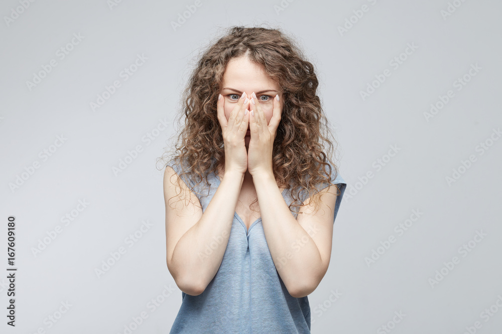 Dissapointed dejected female with hair bun wearing blue loose T-shirt covering her face with hands being tired and exhausted. Desperate woman having depression hiding her crying face with hands Dissapointed dejected female with hair bun wearing blue loose T-shirt covering her face with hands being tired and exhausted. Desperate woman having depression hiding her crying face with hands