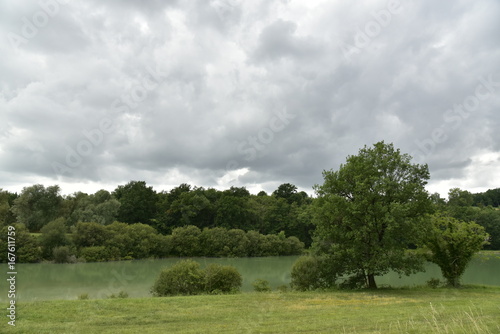 L'étang aux eaux couleur émeraude avec sa nature sauvage qui l'entoure sous un ciel très sombre ,près de Champagne au Périgord Vert