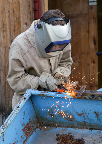 A young welder at work. The worker is engaged in welding parts of the car trailer