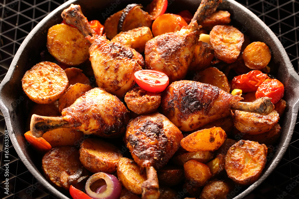 Roasted chicken legs with baked potato on frying pan Roasted chicken legs with baked potato on frying pan