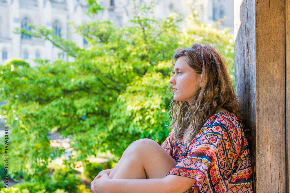 Side profile of young woman sitting on windowsill by garden Side profile of young woman sitting on windowsill by garden