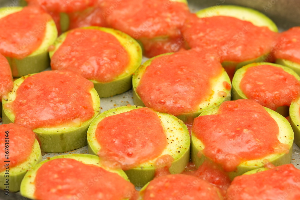 Sliced zucchini topped with tomato sauce before baking