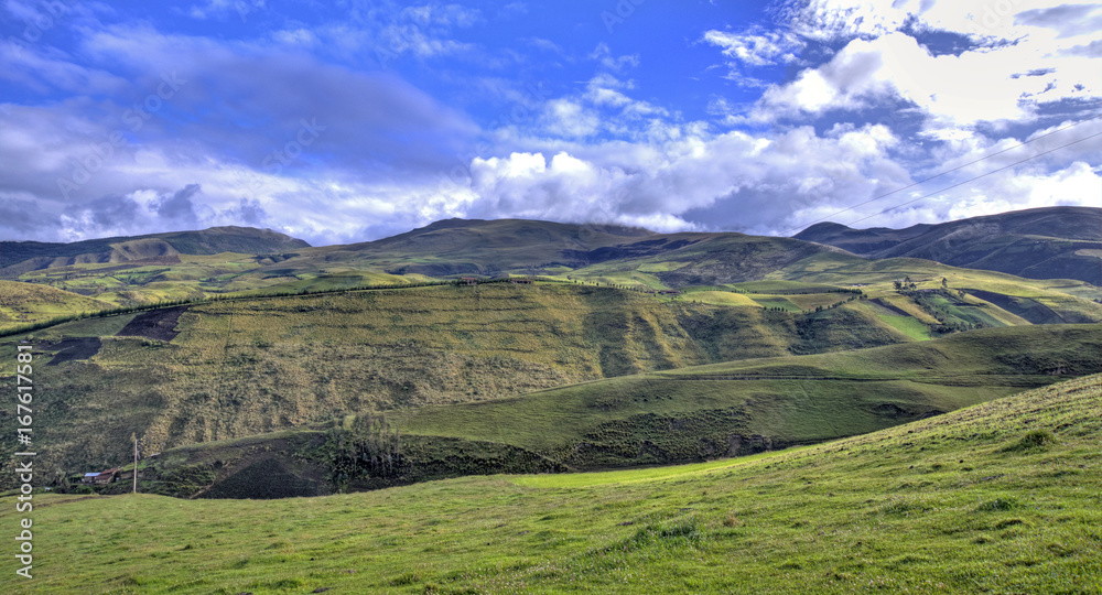 View of a green mountain range, part of the Ecuadorian Andes, with a beautiful sunny and cloudy sky. Cayambe, Ecuador.