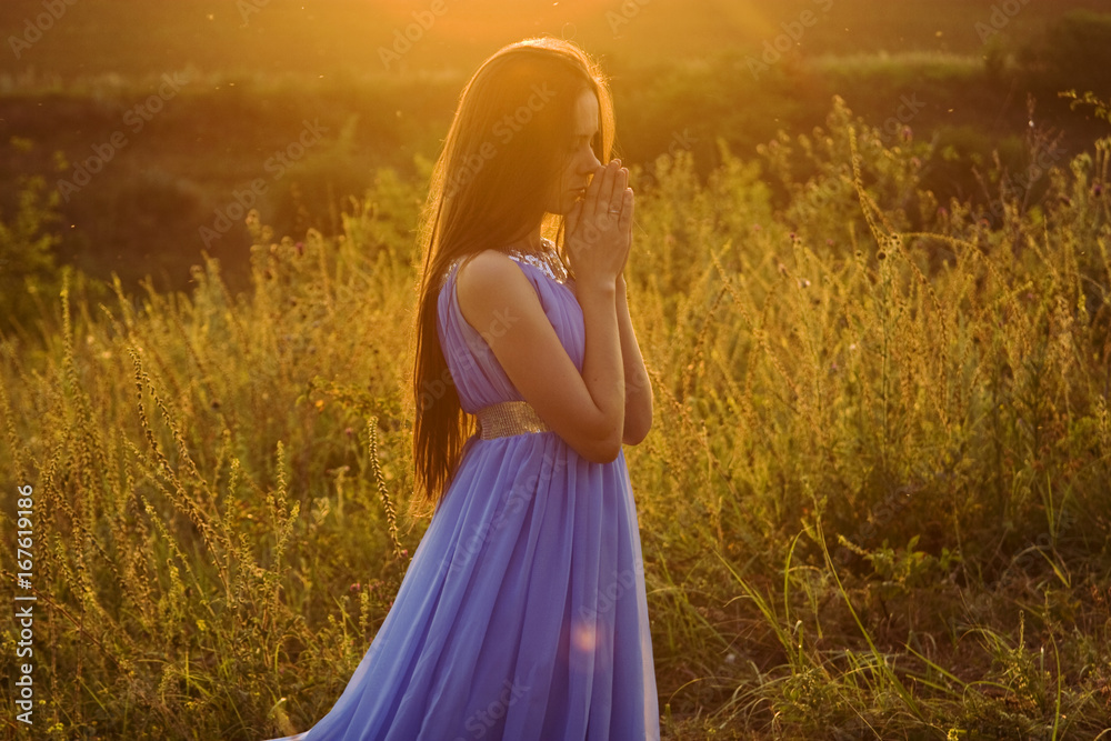 Obraz premium Beautiful, delicate girl at sunset to pray to the Almighty