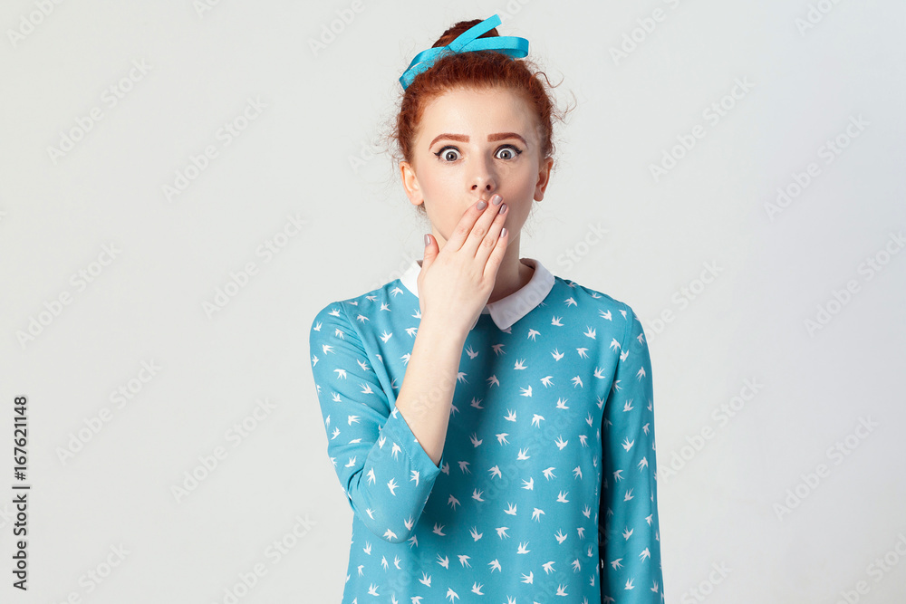 Human face expressions and emotions. Female in despair and shock. The young redhead girl in shoked, looking panic, covered her mouth by hand. Isolated studio shot on gray background. Human face expressions and emotions. Female in despair and shock. The young redhead girl in shoked, looking panic, covered her mouth by hand. Isolated studio shot on gray background.