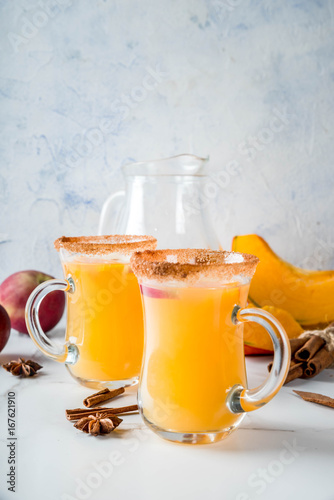 Halloween, Thanksgiving. Traditional autumn, winter drinks and cocktails. Spicy hot pumpkin sangria, with apple, cinnamon, anise. On a white marble table, in glass mugs. Selective focus, copy space
