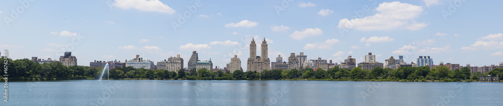 Central Park West skyline and the Jacqueline Kennedy Reservoir in New York City with apartment skyscrapers over lake with fountain in midtown Manhattan and lake reflection 