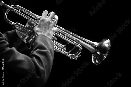Hands of a musician playing on a trumpet closeup in black and white tones on a black background