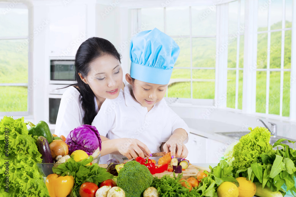 Boy and mother cutting vegetables Boy and mother cutting vegetables