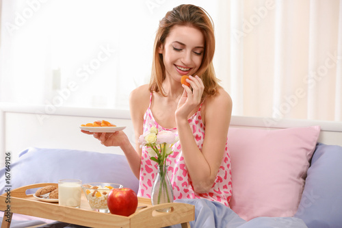 Young pretty woman having delicious breakfast in bed