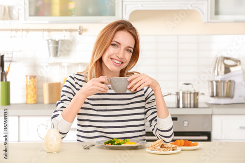 Young pretty woman having delicious breakfast in light kitchen