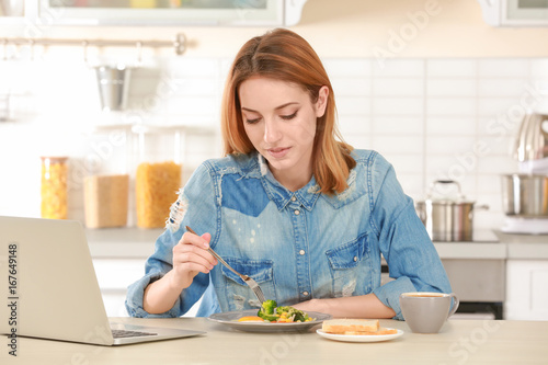 Young woman having breakfast in light kitchen