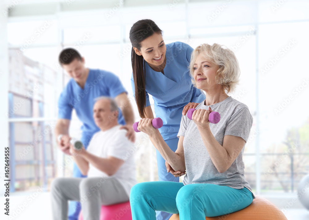 Fototapeta premium Physiotherapists working with elderly patients in modern clinic