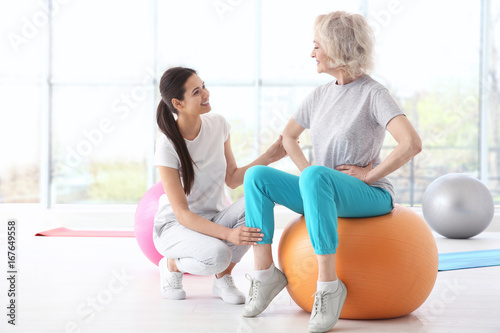 Physiotherapist working with elderly patient in modern clinic
