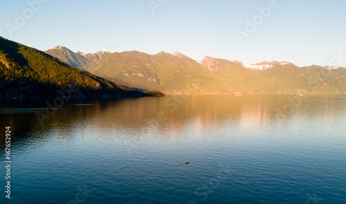 Aerial shot of kayaker on lake with mountains while sunset