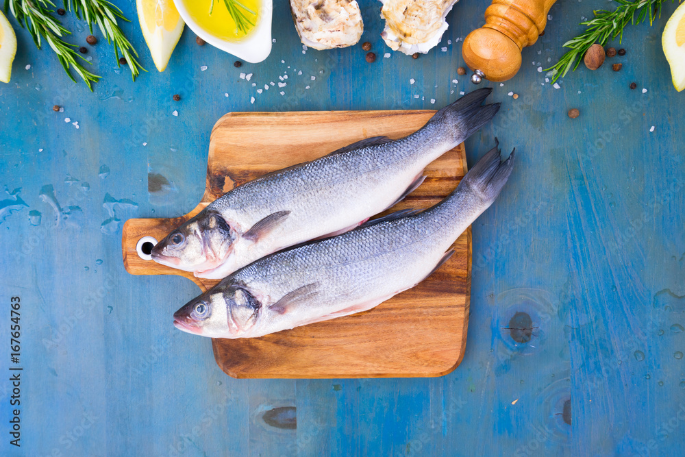 fresh sea fish preparation - top view of two raw seabass fish on cutting board
