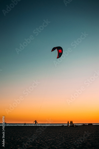 Colorful kite flying against clear blue sky. Low light photo.