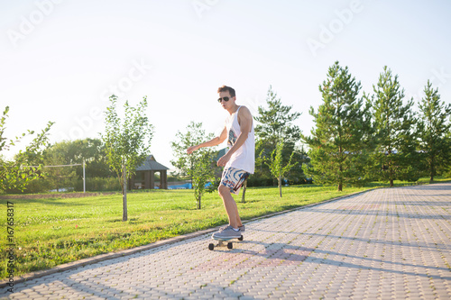 Young skater performing with longboard at sunset in city park. Trendy man having fun with skateboard outdoors, extreme sport concept © 4frame group