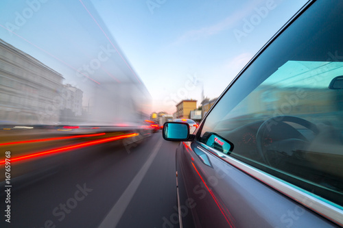 City road view from side car natural sunset light street and other cars is motion blurred