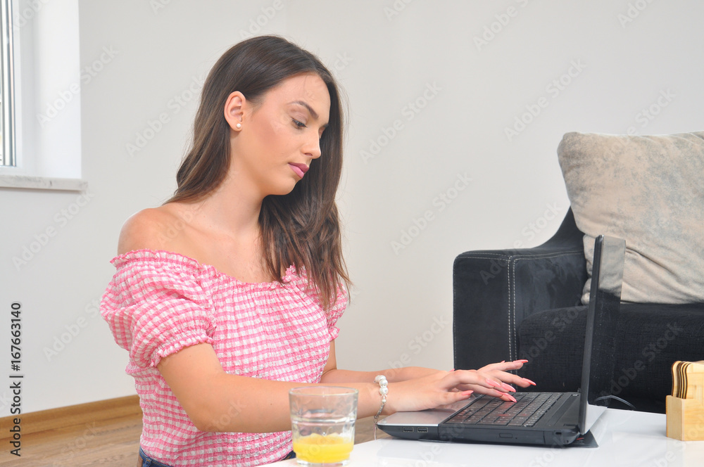 Happy teenage girl is working on a computer at home. Beautiful young woman studying at home on laptop Happy teenage girl is working on a computer at home. Beautiful young woman studying at home on laptop