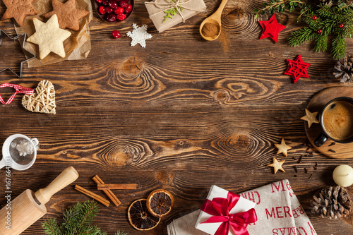 Christmas baking in the form of stars and other decorations: gift with red ribbon, branch of fir tree, cones, cookies, cinnamon, berries, snowflakes. View from above. Copy space