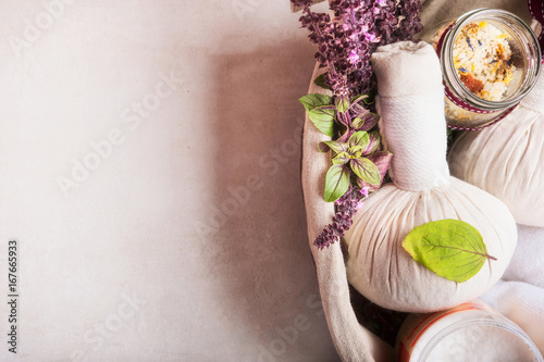 Tableau sur toile Massage setting with herbal compress balls ,fresh herbs and flowers and bathroom salts  on light background,top view