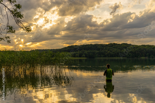 Mann angelt im See, wunderschöner Sonnenuntergang