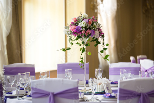 Vase and floral composition on the wedding served table in a restaurant