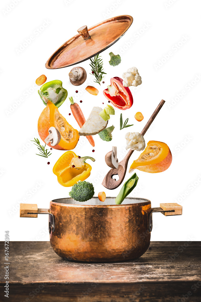 Φωτογραφία Healthy vegetarian eating and cooking with various flying chopped vegetables ingredients, cooking pot and  spoon at wooden table desk , isolated on white background, front view