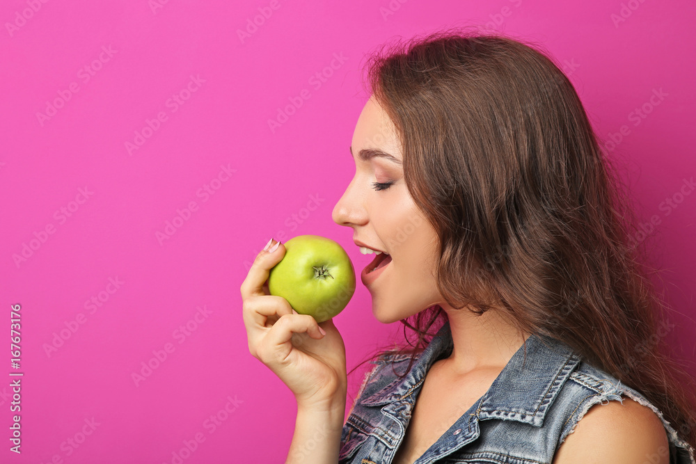 Portrait of young woman with apple on pink background Portrait of young woman with apple on pink background