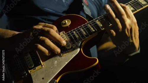 Closeup of man's hands playing electric guitar, smoky scenic