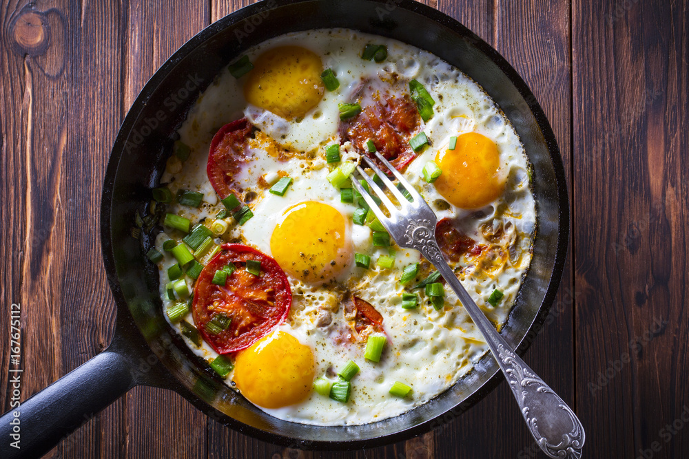 Eggs fried tomatoes in a cast-iron frying pan Wooden vintage background
Eggs fried tomatoes in a cast-iron frying pan Wooden vintage background