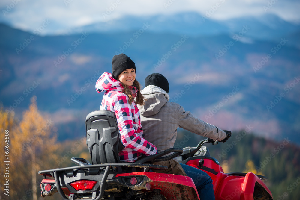 Εκτύπωση καμβά Close-up of guy manages ATV, girl sitting behind him and turned around looking a