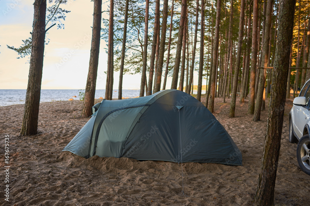 Family holidays, vacations, adventure, travel, activity and adventure concept. Picture of camping place with tent and white car on sandy deserted beach at nature park or forest by the lake or river