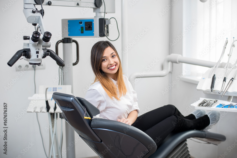 Φωτογραφία Beautiful young female patient with perfect white teeth sitting in dental chair and smiling after treatment at modern dental clinic