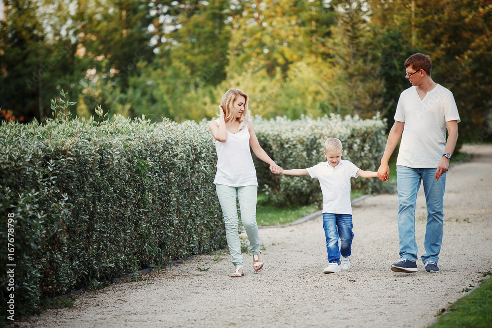 Fototapeta premium Happy young family walking on path in Park holding hands.
