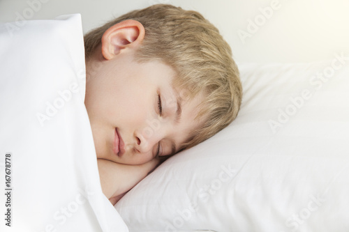 The boy is sleeping in a white bed