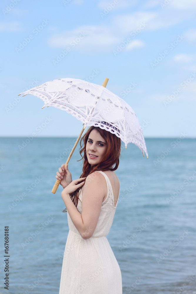portrait of redhead woman at beach with umbrella