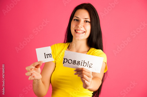 active young woman tearing apart text impossible over pink background