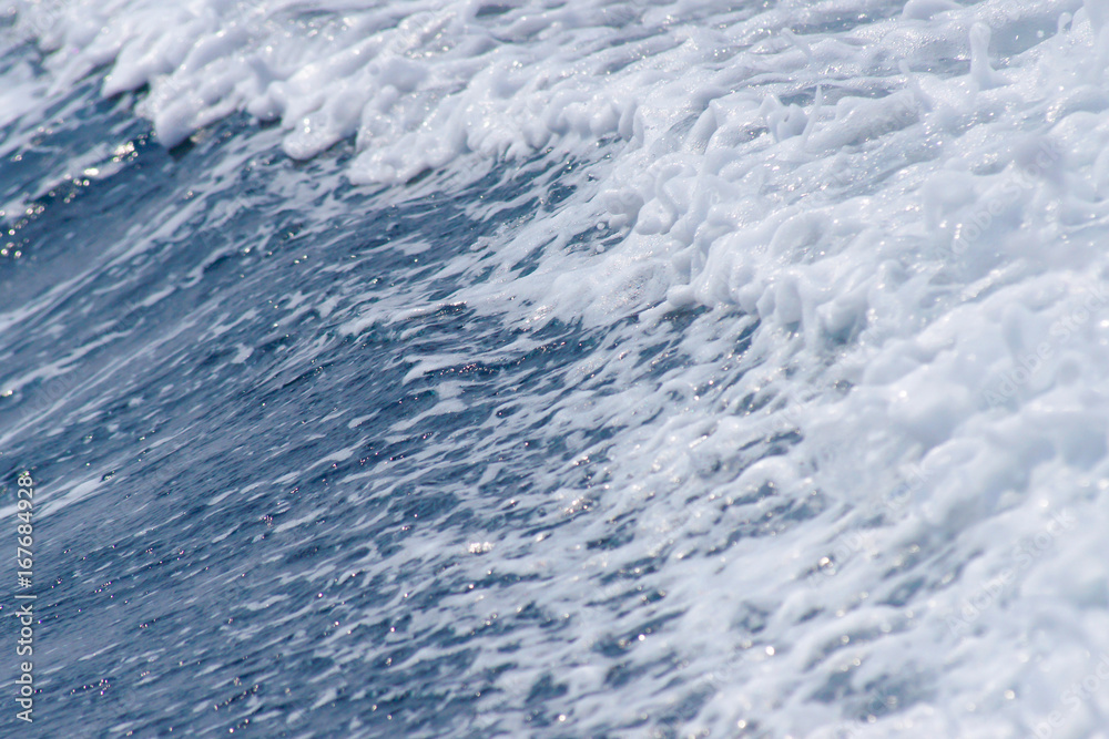 The wave of blue sea with foam on the surface made from boat engine