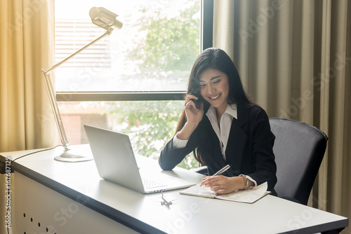 Happy business woman talking on the phone in office