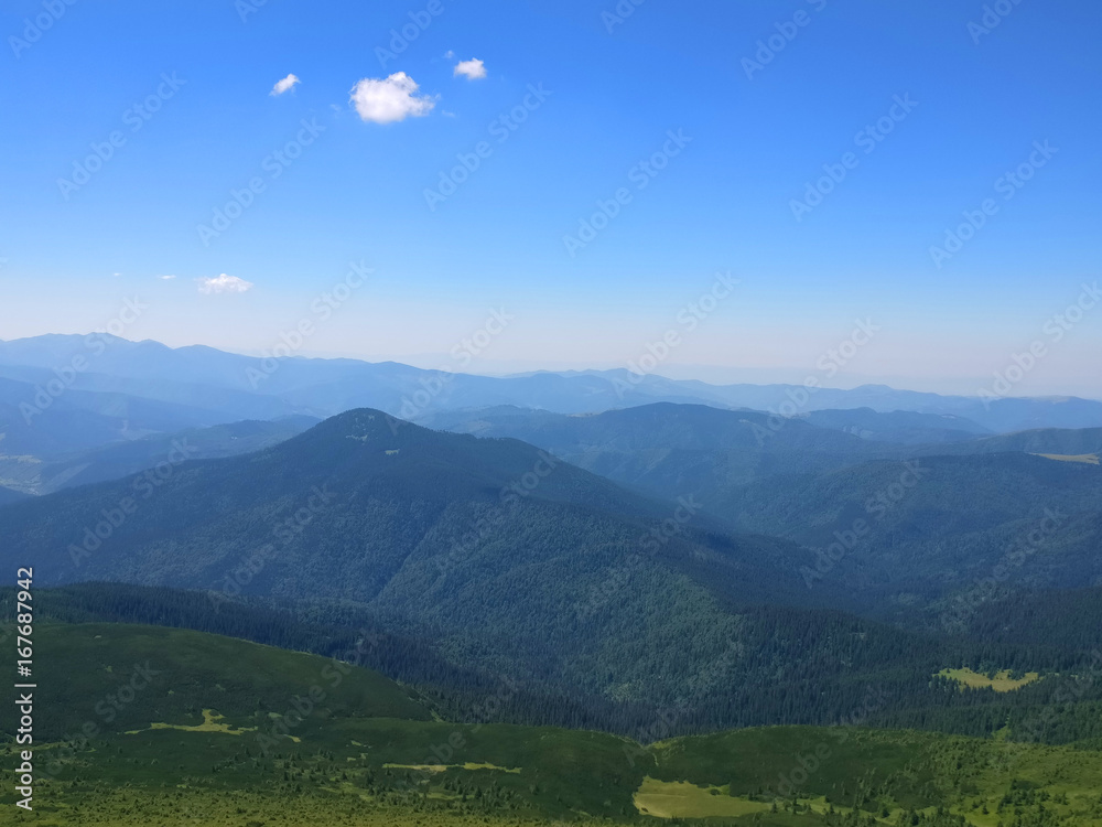 Peaceful green mountains covered of grass under the clear blue sky